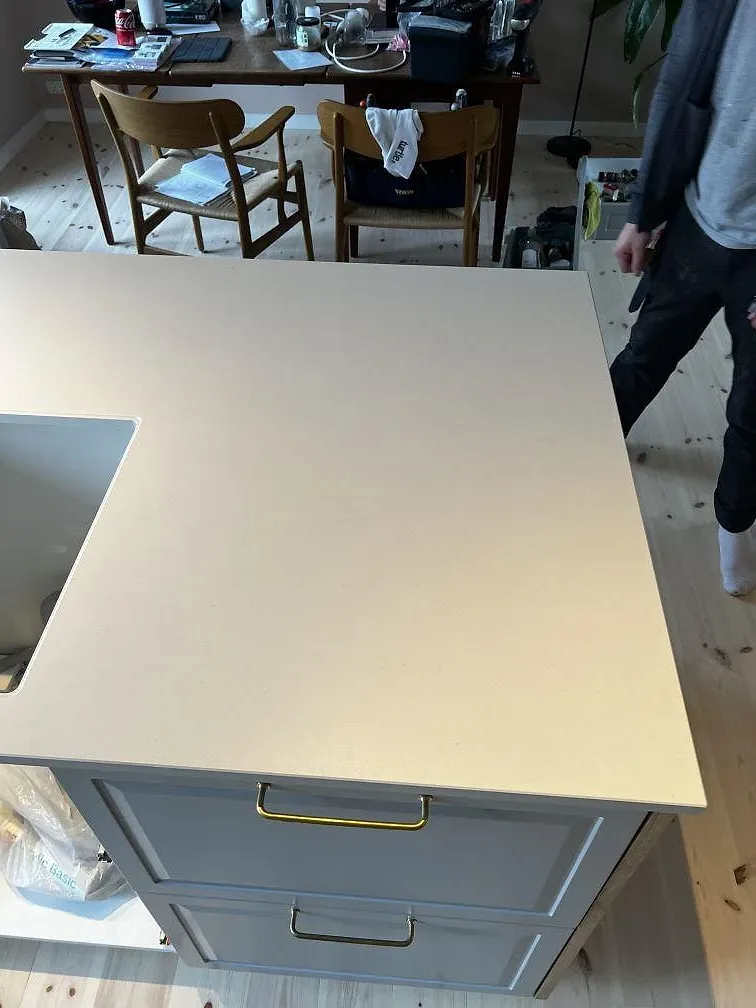 Stor ljus yta i matt Dekton Aeris keramik på köksbänk under montering med person i rummet i Kgs. Lyngby.
