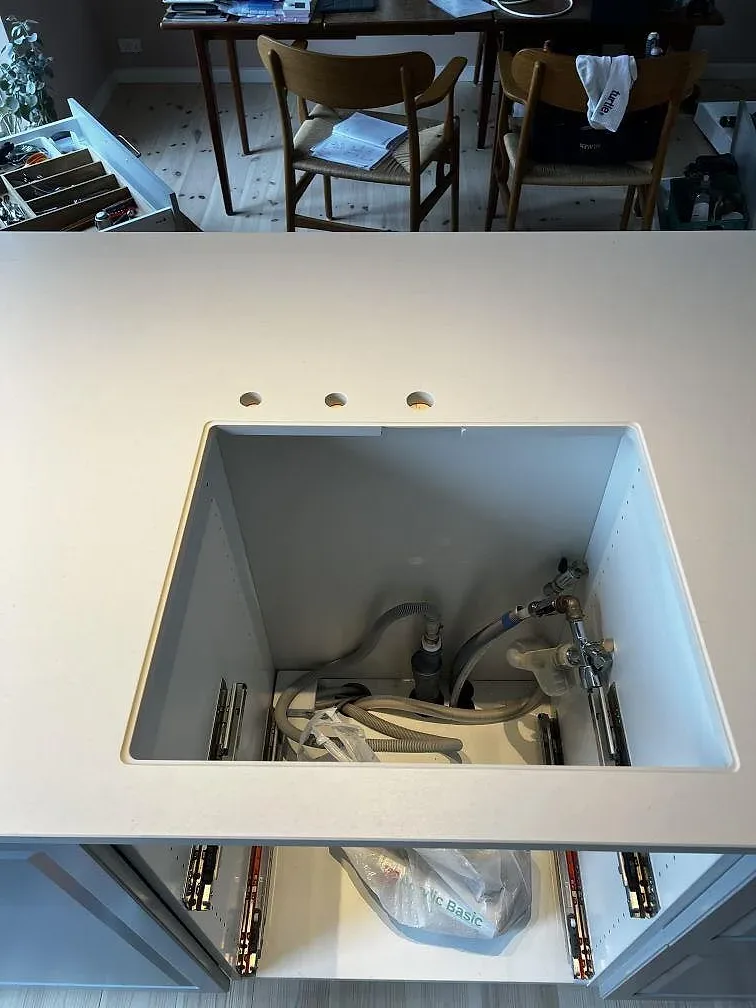 Matt Dekton Aeris köksbänkskiva med förberedd öppning, tapphål och öppna skåpstommar under montering i Kgs. Lyngby.