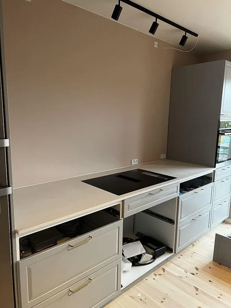 L-formad köksbänkskiva i matt Dekton Aeris keramik med svart induktionshäll och ljusa köksstommar i Kgs. Lyngby.