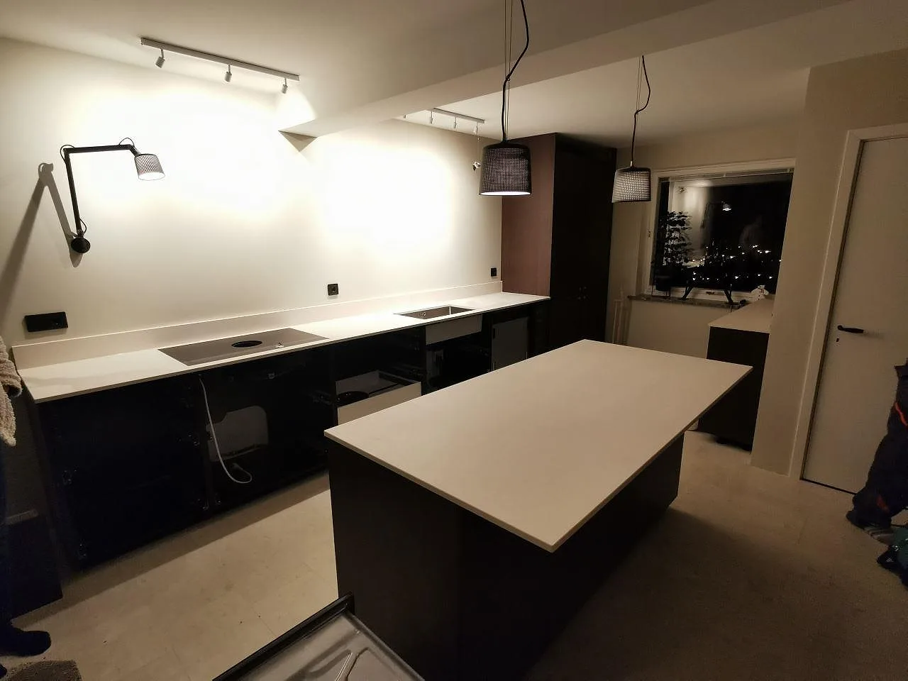 Köksbänkskiva och köksö i vit Dekton Aeris, matt yta, med planmonterad spishäll och underlimmad diskho i ett kök i Lund.
