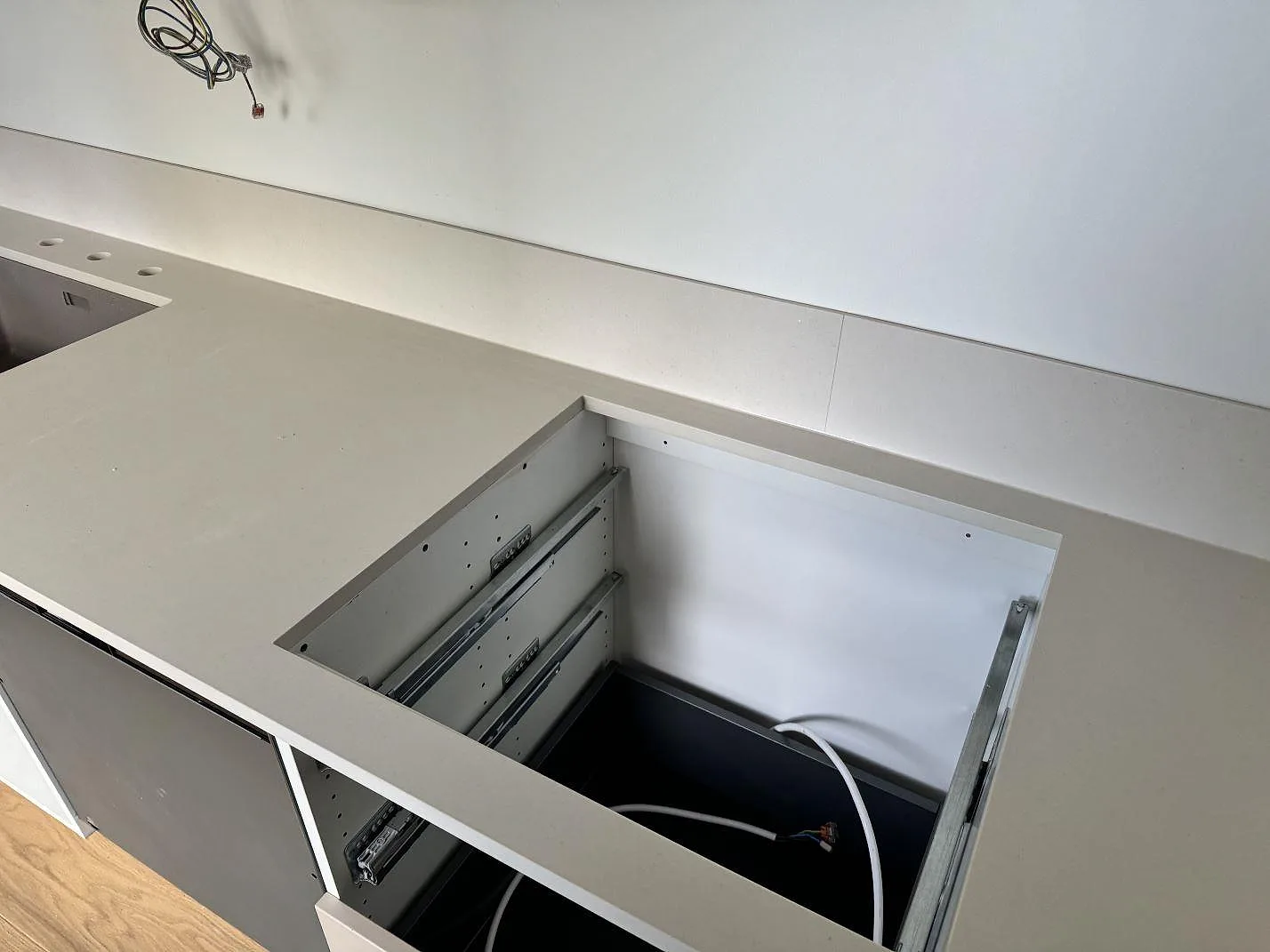 Köksbänkskiva i matt keramisk Dekton Aeris med låg stänkkant och öppen stomme under montering i Malmö.