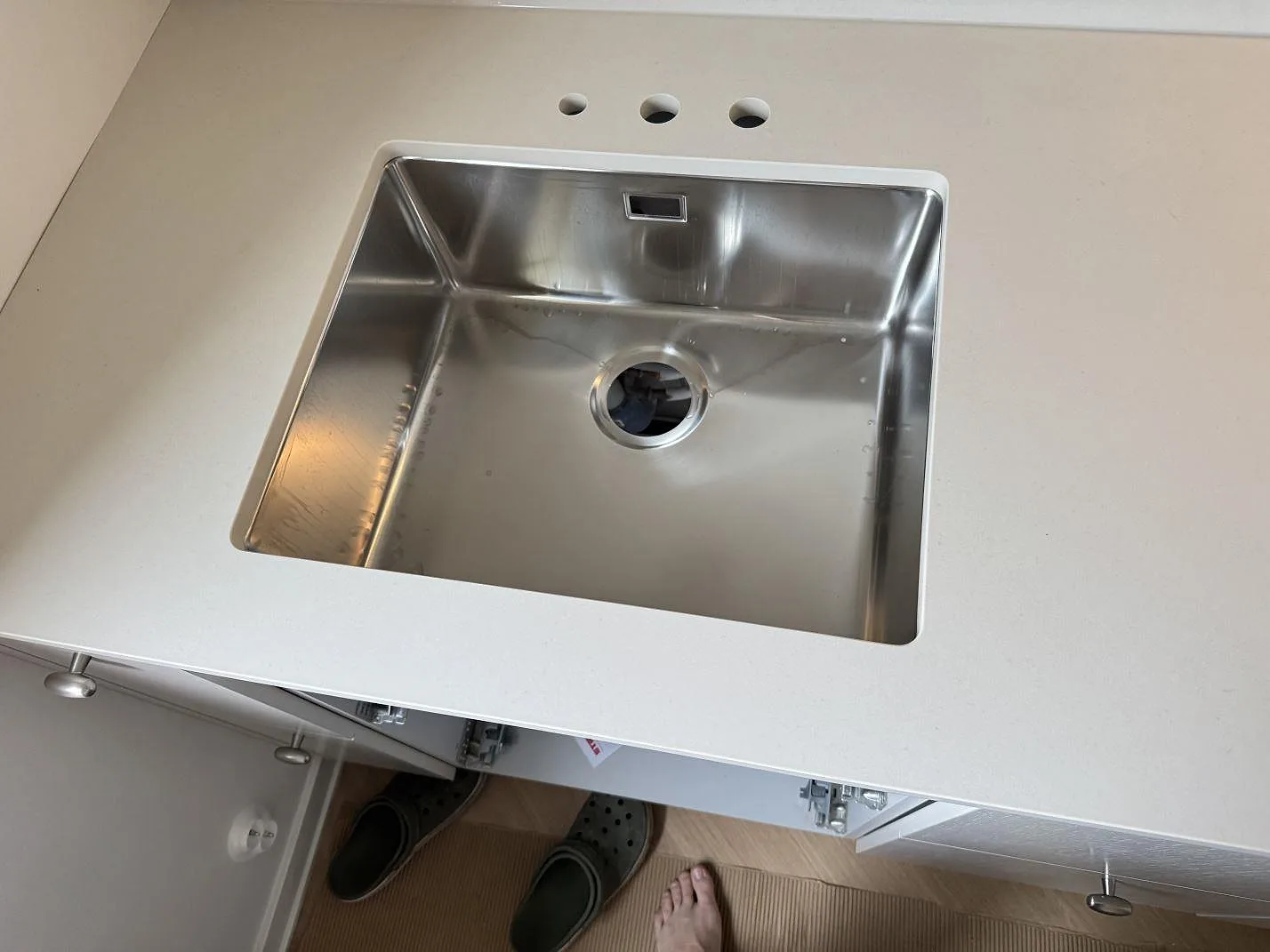 Rostfri diskho i ljus matt Dekton Aeris bänkskiva med tre blandarhål under montering i Malmö.