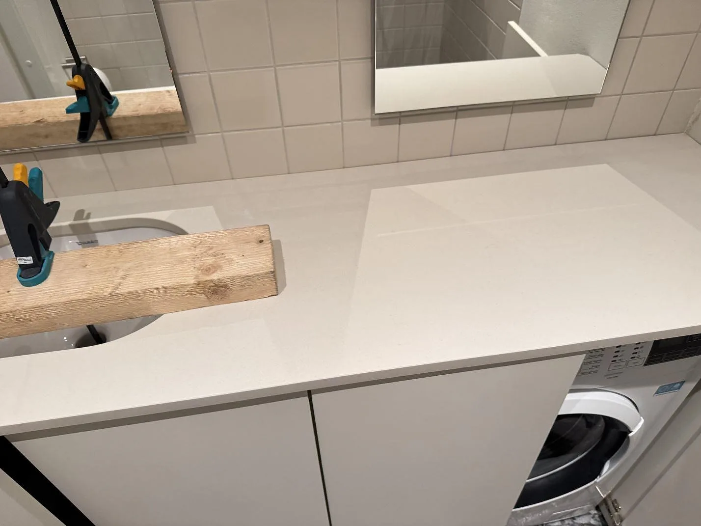 Bänkskiva i matt Dekton Aeris keramik vid tvättställ och speglar i en badrumsmiljö i Malmö.