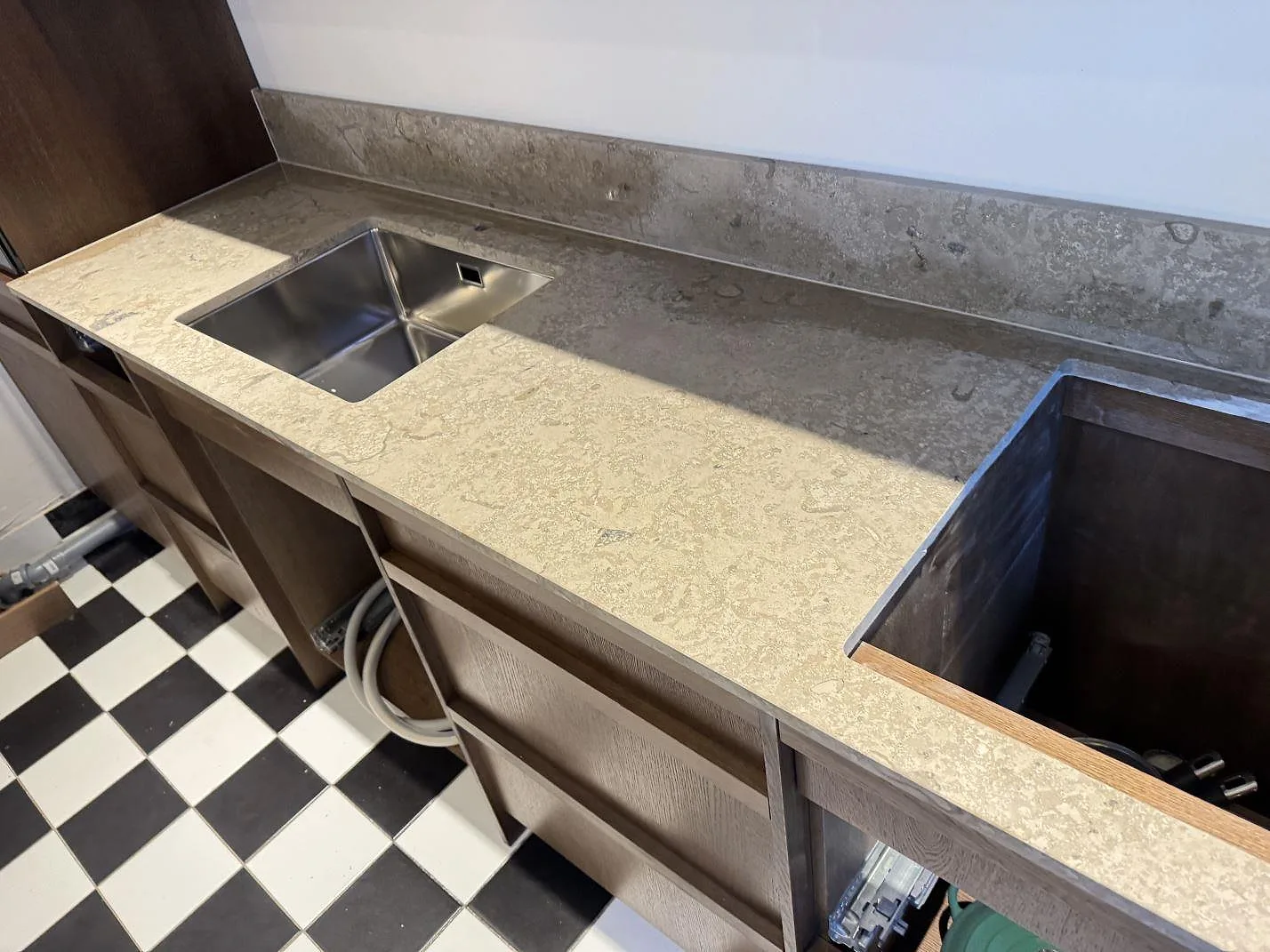 Lång köksbänk i matt Dekton Aeris keramik med rostfri diskho, stänkkant och öppna skåpsstommar i Malmö.