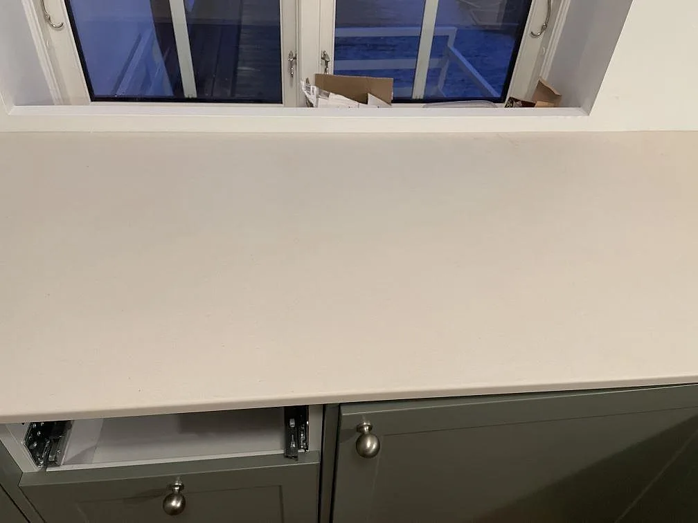 Matt Dekton Aeris bänkskiva med öppna lådstommar under montering vid fönstret i Tjörnarp.