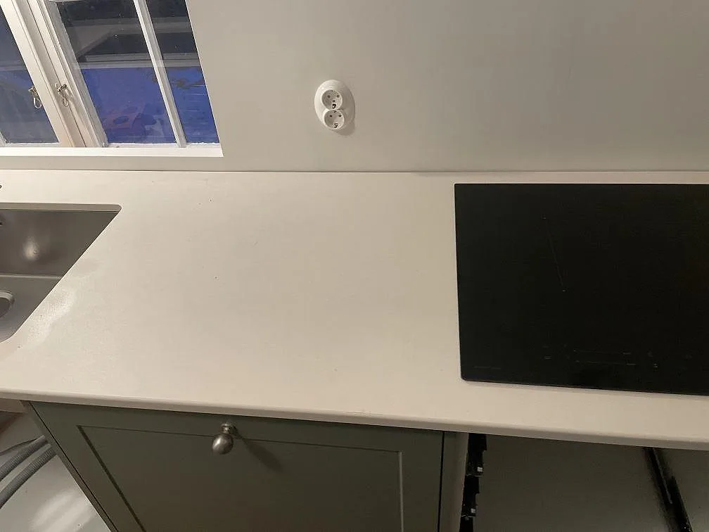 Matt Dekton Aeris bänkskiva med infälld induktionshäll och diskho längs köksväggen i Tjörnarp.