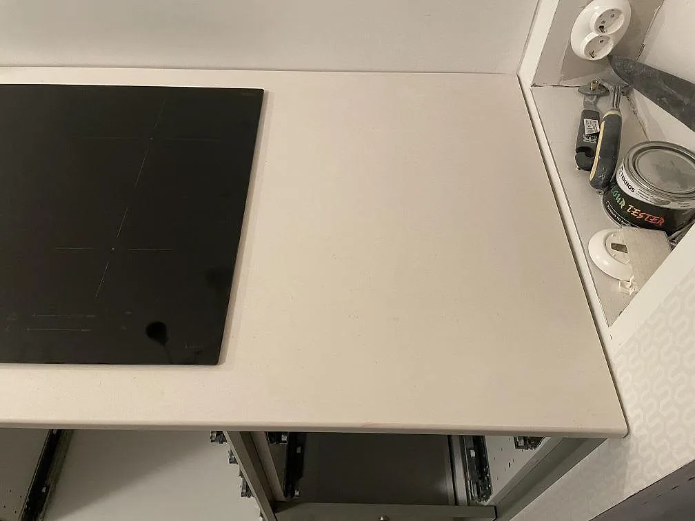 Infälld induktionshäll i matt Dekton Aeris köksbänkskiva i ett kök under montering i Tjörnarp.