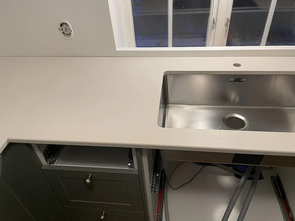 Underlimmad rostfri diskho i matt Dekton Aeris köksbänkskiva vid fönstret i ett kök i Tjörnarp.
