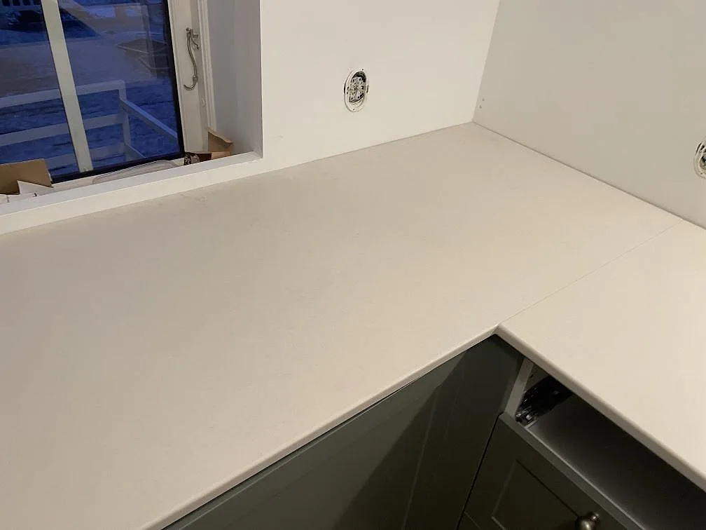 Matt Dekton Aeris köksbänkskiva i hörnet vid fönstret med diskret ådring i ett kök i Tjörnarp.
