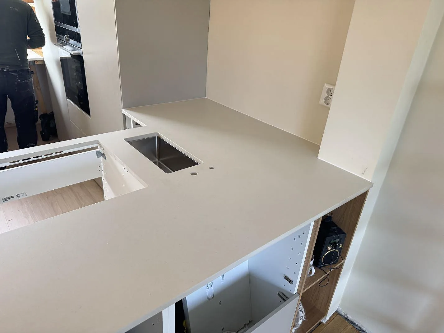 Köksbänkskiva i matt Dekton Aeris keramik med synlig diskho, armaturhål och öppna stommar i Ystad.