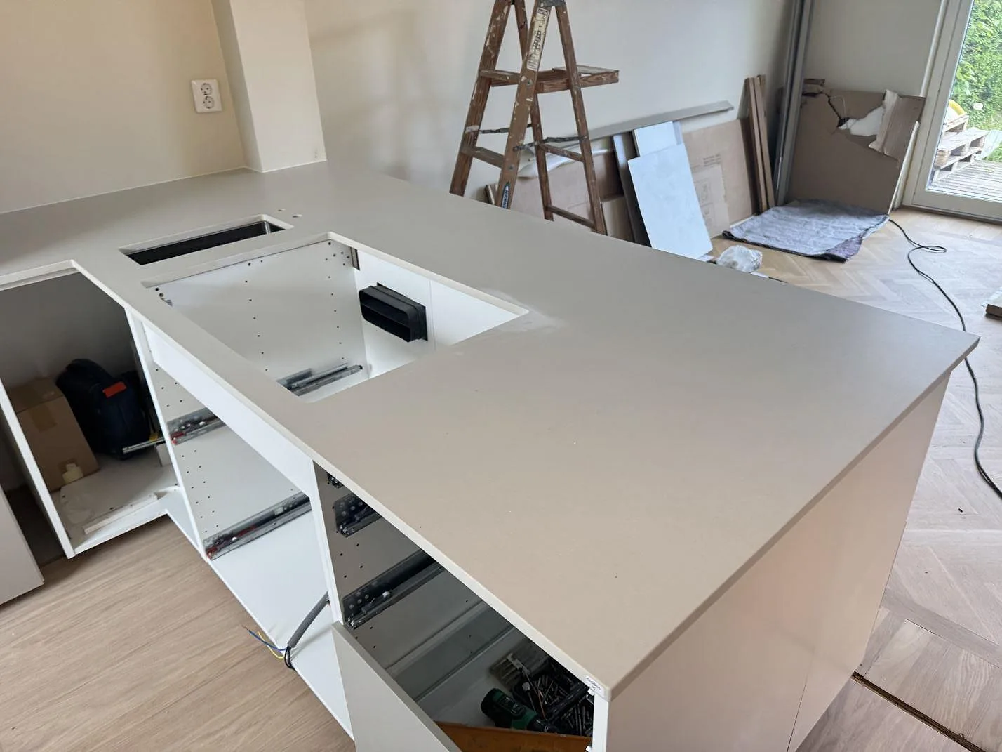 Matt Dekton Aeris som ljus köksbänkskiva över öppna stommar, med urtag och arbetsyta i Ystad under montering.