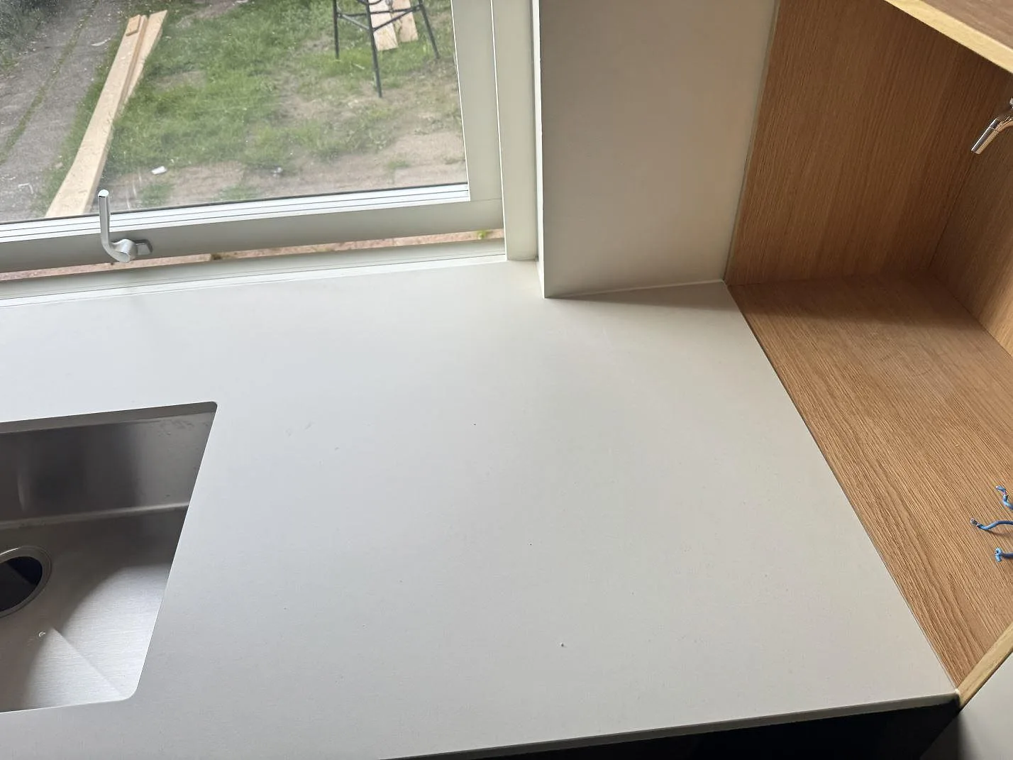 Detalj av matt Dekton Aeris vid fönster och träinredning, med diskzon i köket i Ystad.