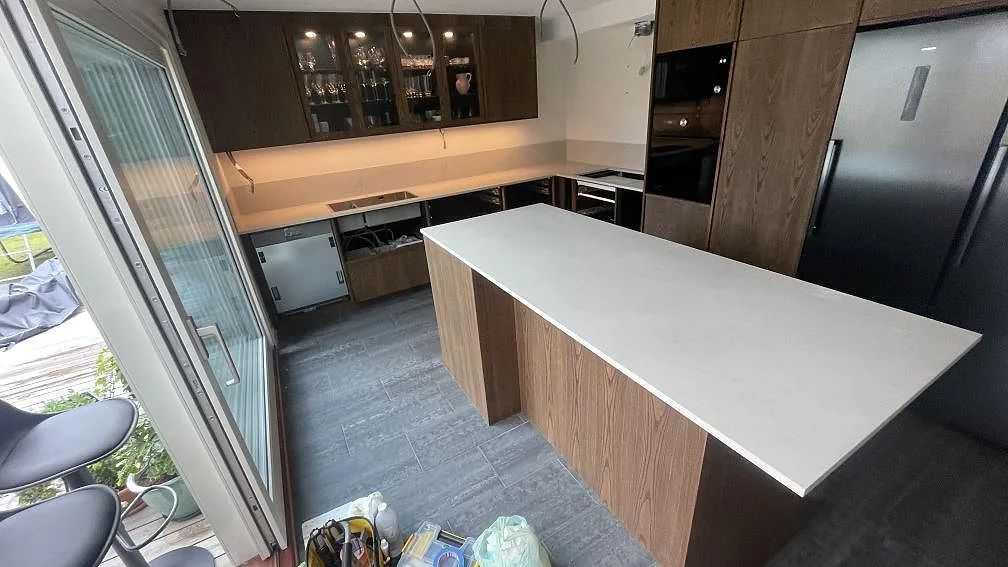 Köksbänkskiva och köksö i matt Dekton Albarium, keramik, med häll och lågt stänkskydd i ett kök i Billdal.
