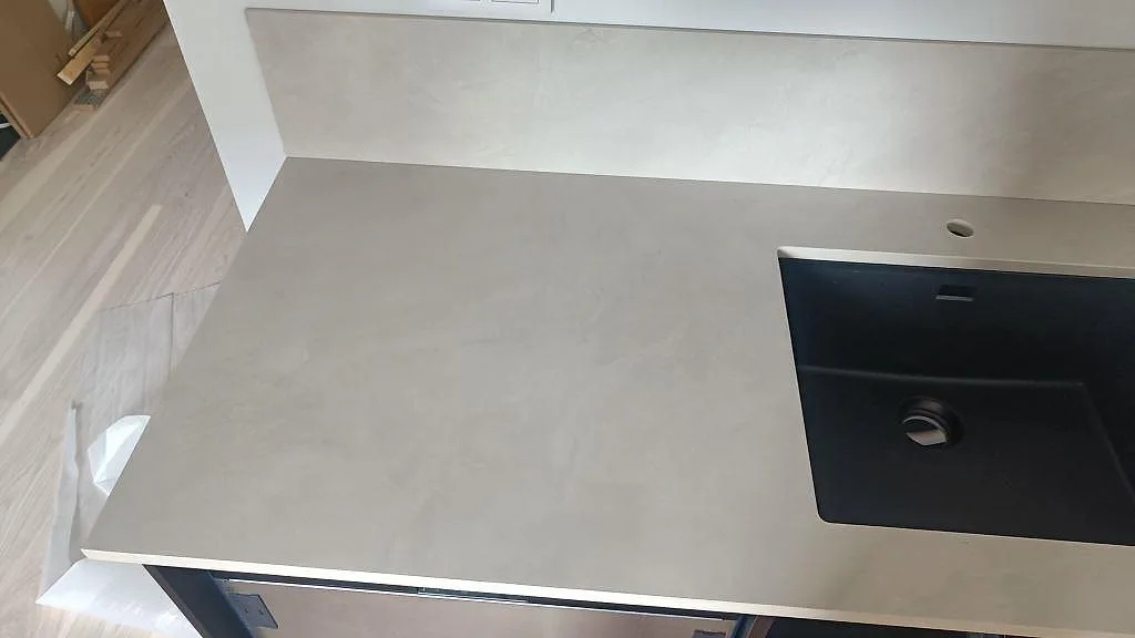 Bänkskiva i matt Dekton Albarium keramik med synlig beigegrå yta, svart diskho och 8 mm stänkskydd i Bunkeflostrand.