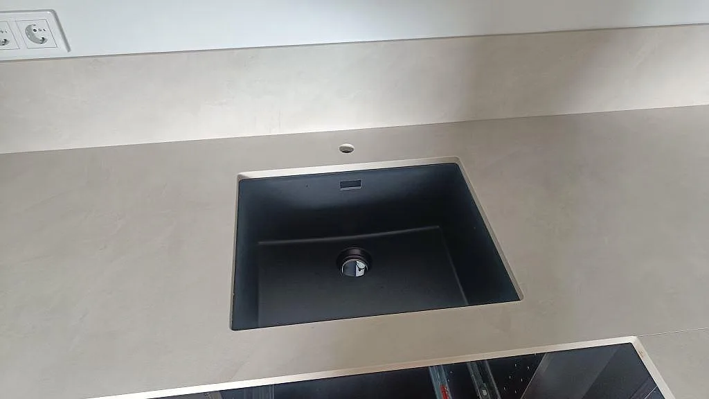 Svart underlimmad diskho monterad i matt Dekton Albarium keramik med låg stänkkant i ett kök i Bunkeflostrand.
