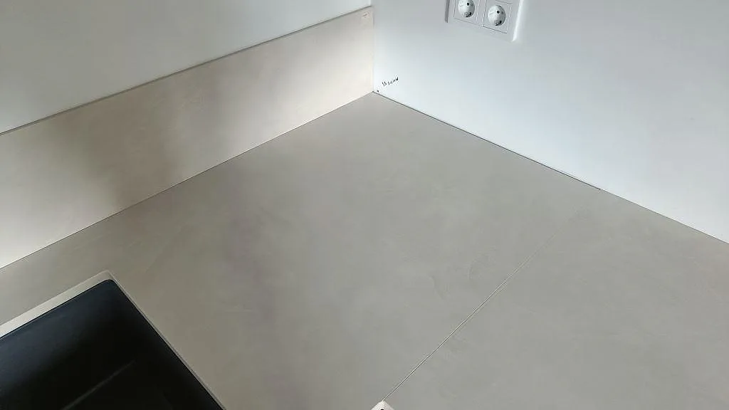 Hörndel av L-formad köksbänkskiva i matt Dekton Albarium keramik med stänkskydd längs väggen i Bunkeflostrand.