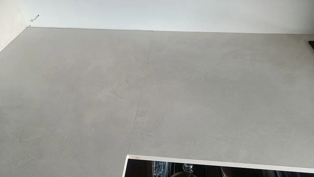 Detalj av matt Dekton Albarium bänkskiva med skarv, stänkskydd och den ljusa keramiska ytan i köket i Bunkeflostrand.
