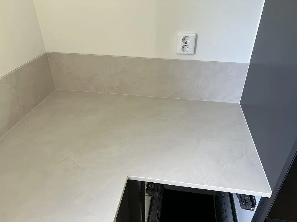 Hörn av köksbänkskiva i matt Dekton Albarium med uppvikt stänkskydd och ljus keramik i Höllviken.