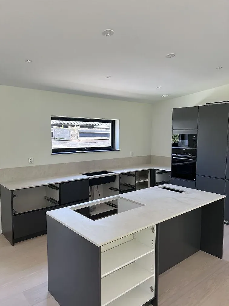Köksbänkskiva i matt Dekton Albarium, ljus keramik, på köksö och väggbänk under montering i Höllviken.