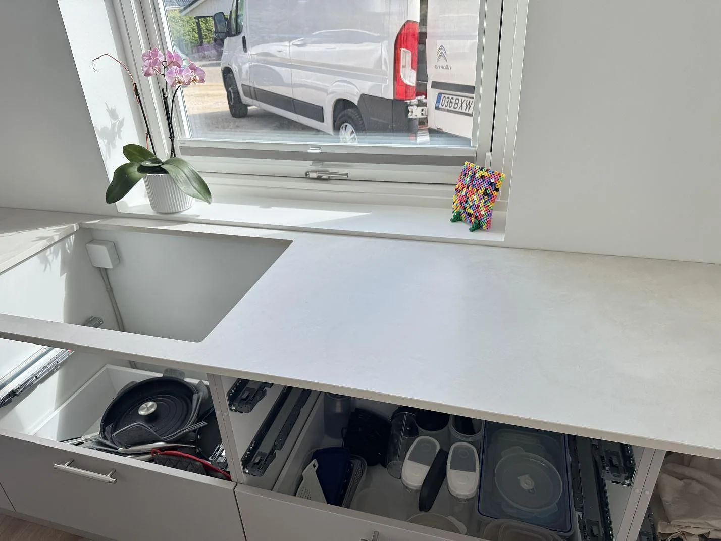 Köksbänk i matt Dekton Albarium, ljus keramik, med synligt diskhoparti och fönsterbräda i ett kök i Hørsholm.
