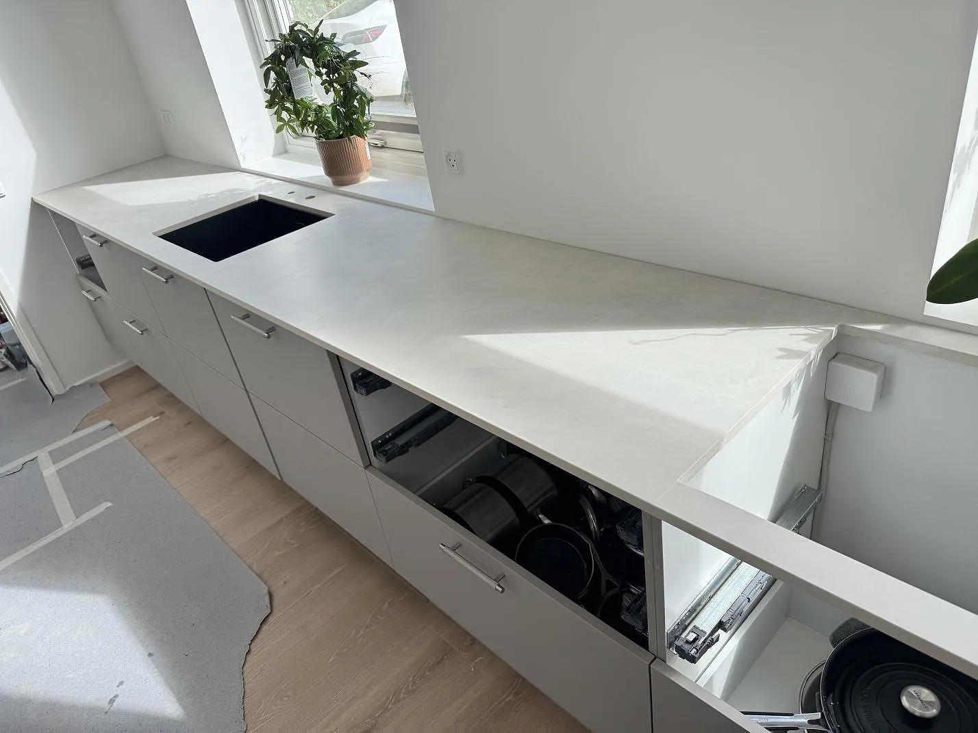 Köksbänkskiva i matt Dekton Albarium, 20 mm keramik, med diskhodel, fönsternisch och öppna kökslådor i Hørsholm.