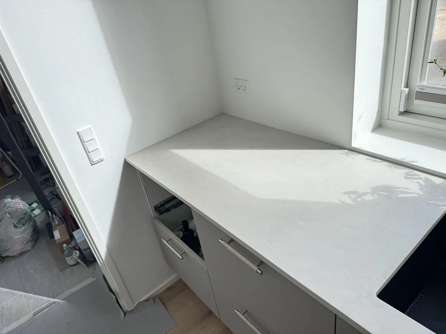 Ändparti av matt Dekton Albarium köksbänkskiva med ljus stenyta, diskhokant och öppna stommar i Hørsholm.