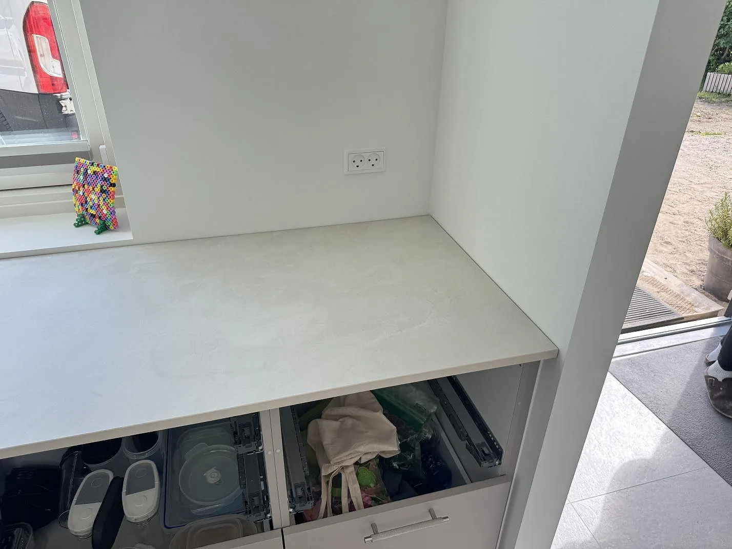 Installerad köksbänkskiva i matt Dekton Albarium, ljus keramik, med fönsternisch och öppen förvaring i Hørsholm.