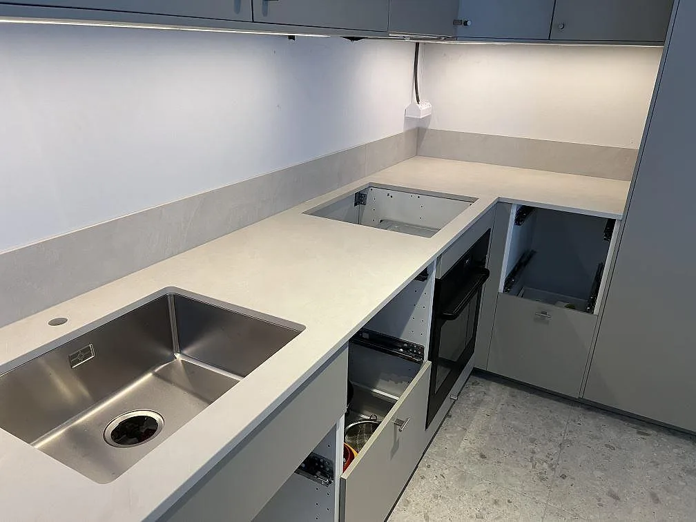 Närbild på matt köksbänkskiva i Dekton Albarium keramik med rostfri diskho, hällöppning och låg stänkkant i Vällingby.