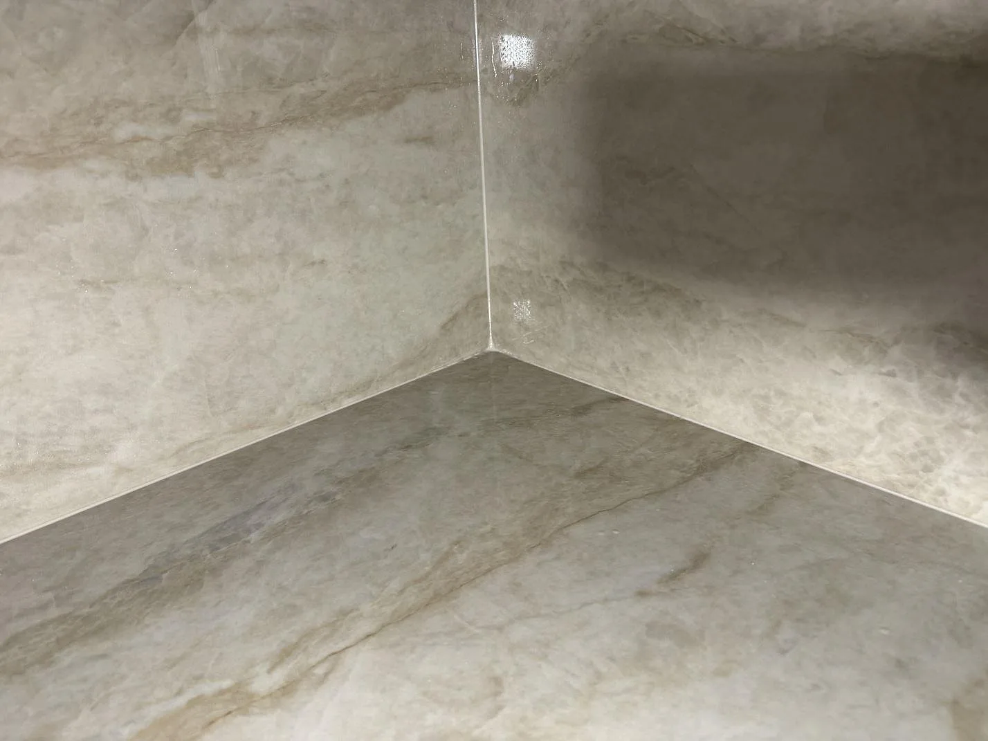 Detalj av hörn och ådring i polerad Dekton Arga på köksbänkskiva och väggskiva i Åryd.