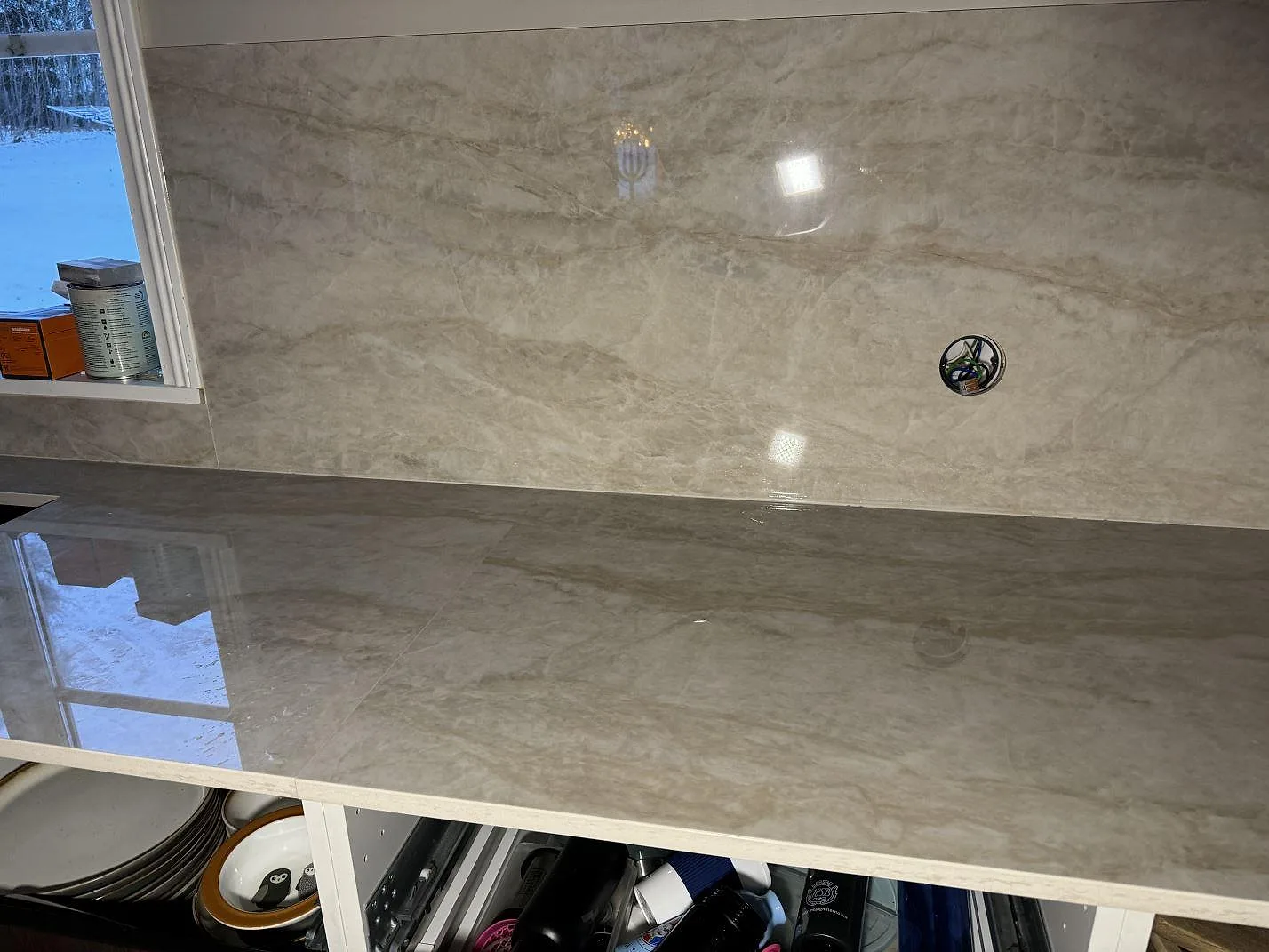 Polerad Dekton Arga som köksbänkskiva och hög väggbeklädnad med blandarhål i ett kök i Åryd.