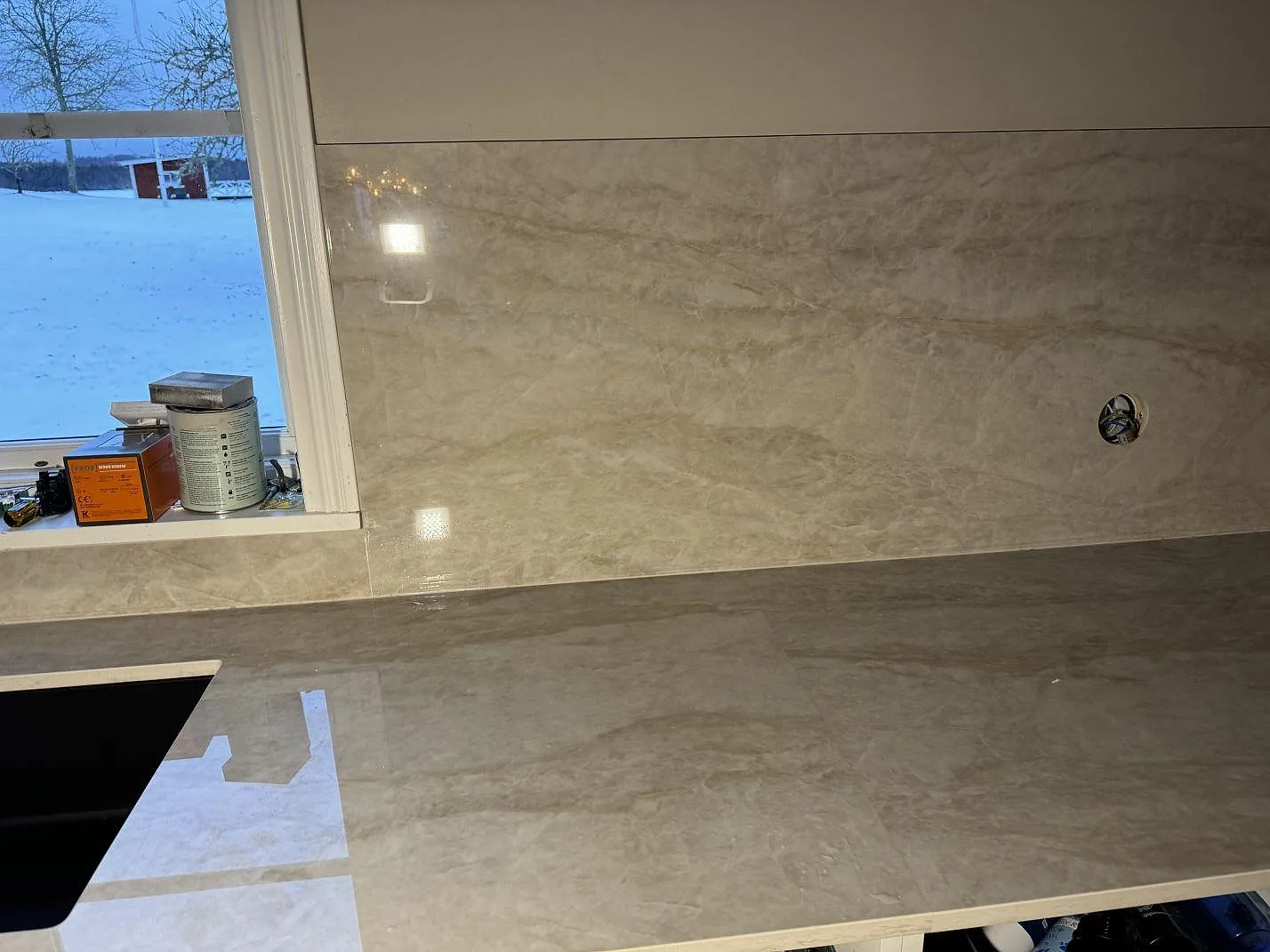 Närbild på svart underlimmad diskho i polerad Dekton Arga med gråbeige ådring i kök i Åryd.