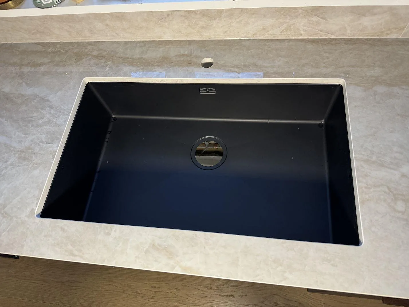 Toppvy av svart underlimmad diskho monterad i polerad Dekton Arga i kök i Åryd.