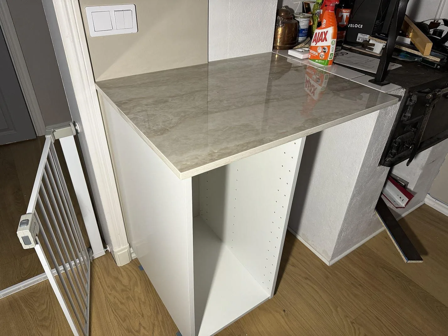 Separat arbetsyta i polerad Dekton Arga på vit köksstomme under montering i Åryd.