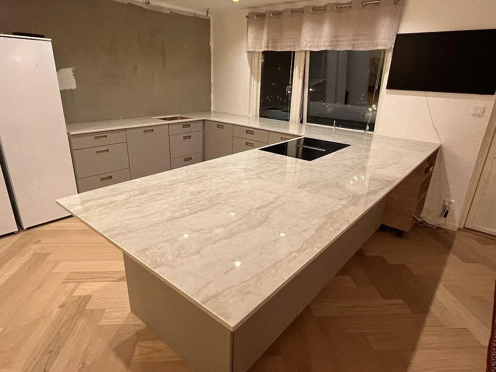 Köksbänkskiva i polerad Dekton Arga, 20 mm keramik, med stor köksö, häll och fiskbensgolv i ett kök i Älvsjö.