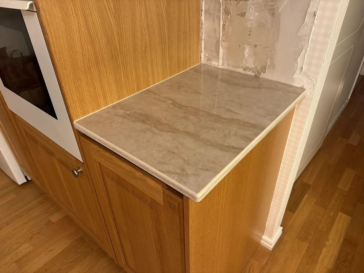 Separat arbetsyta i polerad Dekton Arga vid träinredning och vägg under montering i Ängelholm.