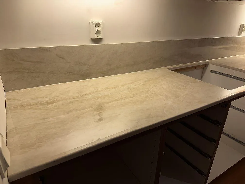 Rak köksbänkskiva i polerad Dekton Arga med uppvikt stänkskydd och öppen trästomme i Ängelholm.