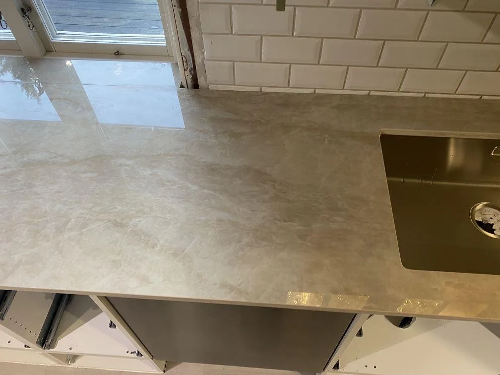 Polerad Dekton Arga keramik på köksbänk med synlig diskho och blank ådrad yta i ett kök i Alingsås.