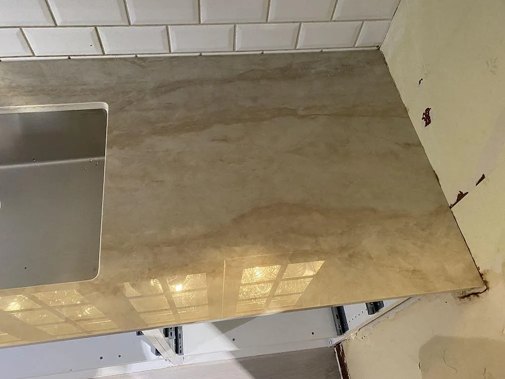 Detalj av polerad Dekton Arga keramik vid diskho och väggavslut, med varm ådring i köket i Alingsås.