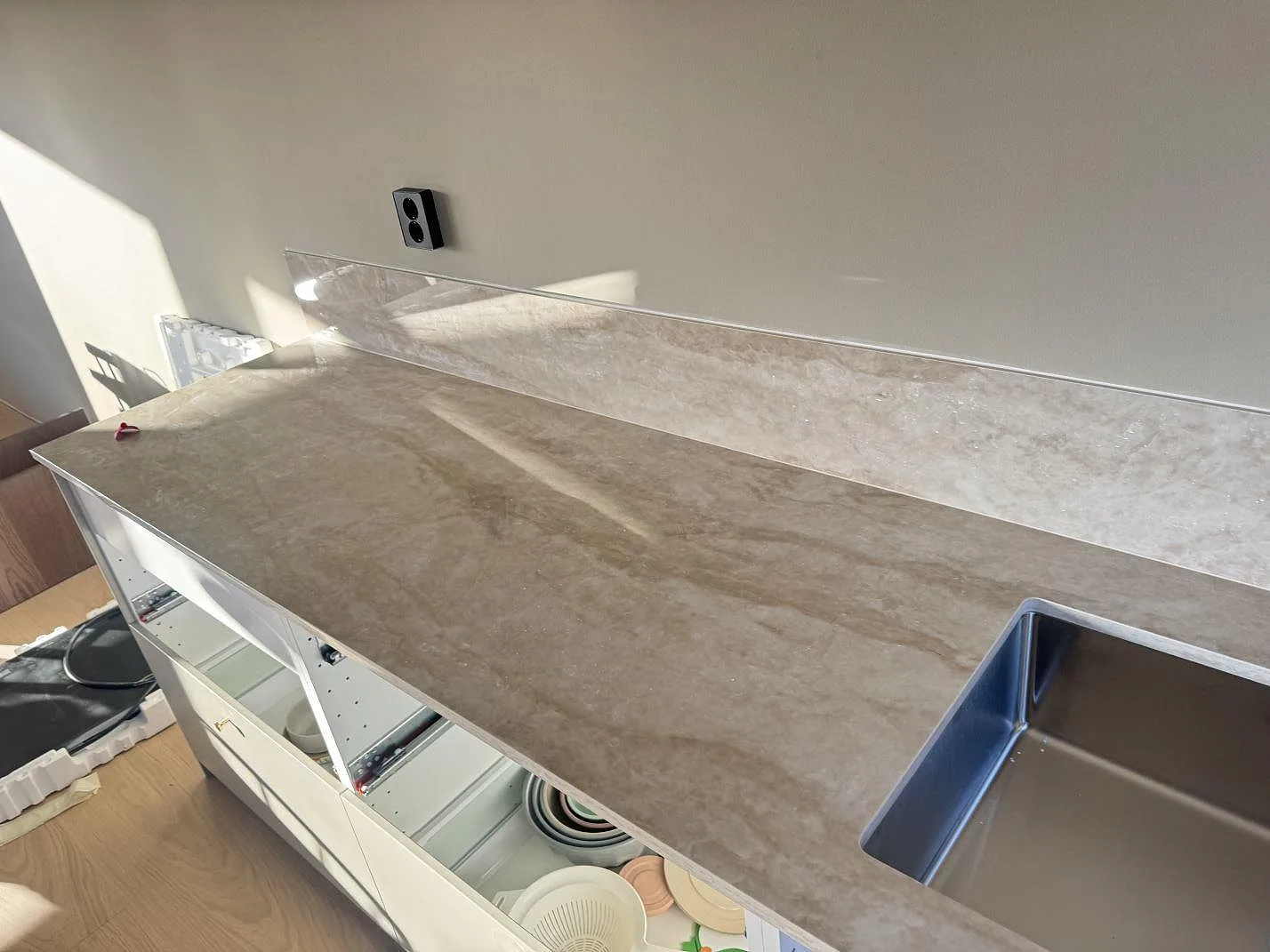Lång köksbänkskiva i polerad Dekton Arga med matchande stänkkant och diskho i ett kök i Bankeryd.