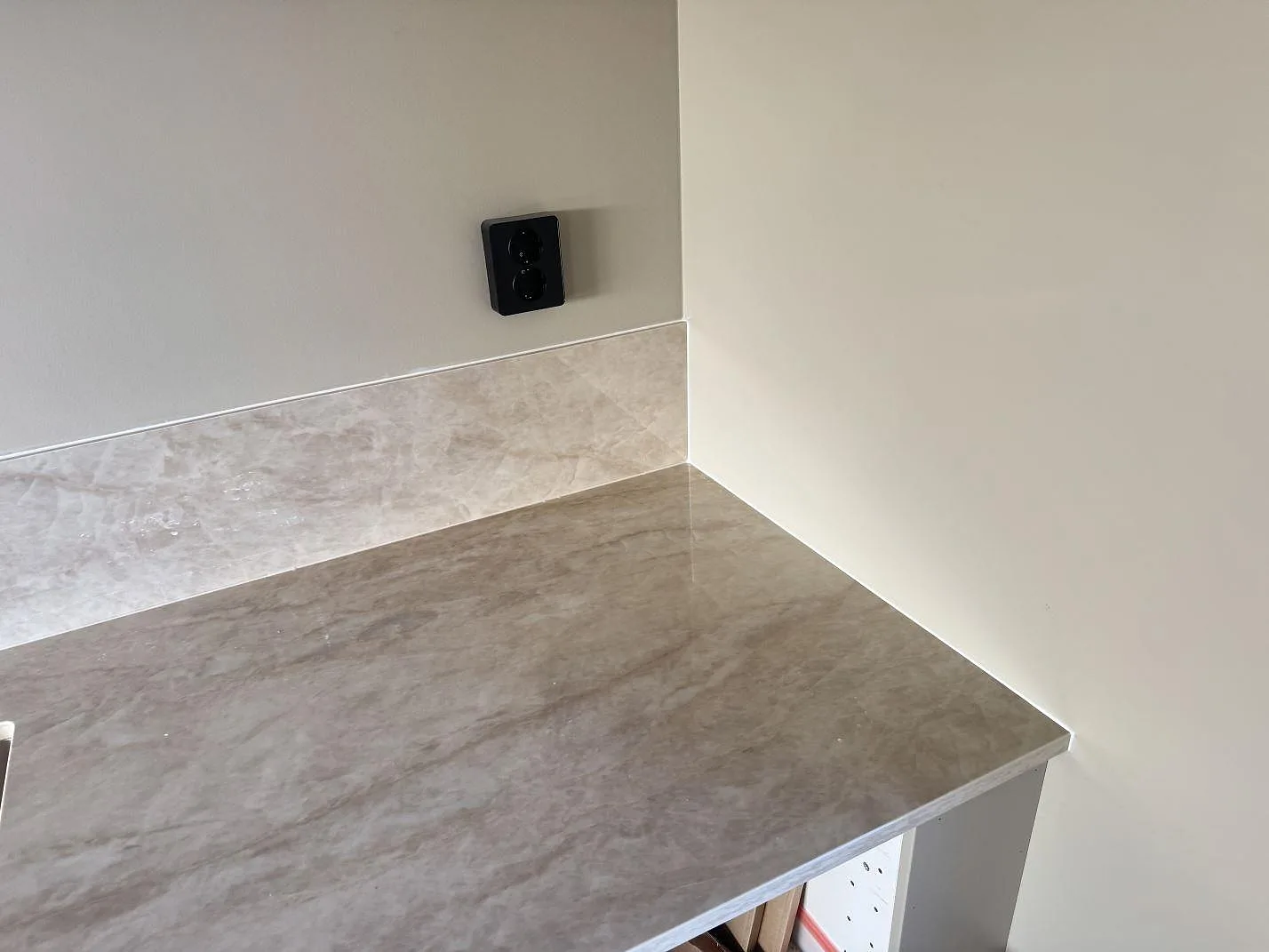 Hörndetalj med polerad Dekton Arga bänkskiva och matchande 8 mm stänkkant mot vägg i kök i Bankeryd.