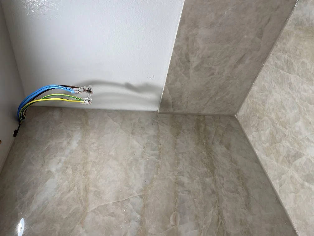 Detalj av polerad Dekton Arga bänkskiva och stänkskydd vid kökshörn under montering i Billdal.