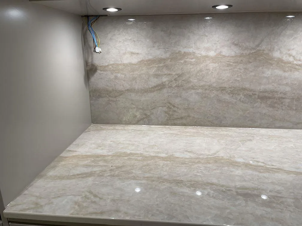 Polerad Dekton Arga som bänkskiva och uppvikt stänkskydd under överskåp i ett kök i Billdal.
