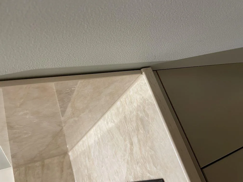 Kantdetalj vid vägg och skåp med polerad Dekton Arga bänkskiva i köket i Billdal.