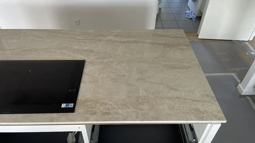 Ovanifrån på köksö i polerad Dekton Arga med svart häll och varm krämbeige ådring i Brøndby Strand.