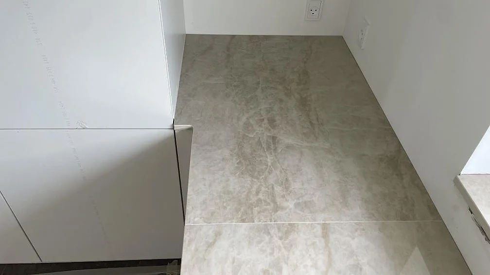 Sidobänk i polerad Dekton Arga vid högskåp, krämbeige keramik med mjuk ådring i ett kök i Brøndby Strand.