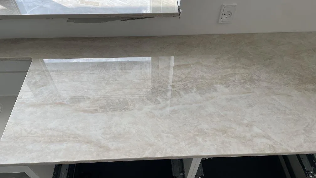 Detalj av polerad Dekton Arga arbetsyta vid diskbänken, med fönsterreflektion och öppna köksstommar i Brøndby Strand.