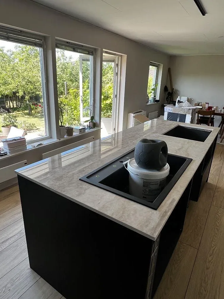Polerad köksbänkskiva i Dekton Arga med underlimmad diskho, hälluttag och stora fönster under montering i Bromölla.