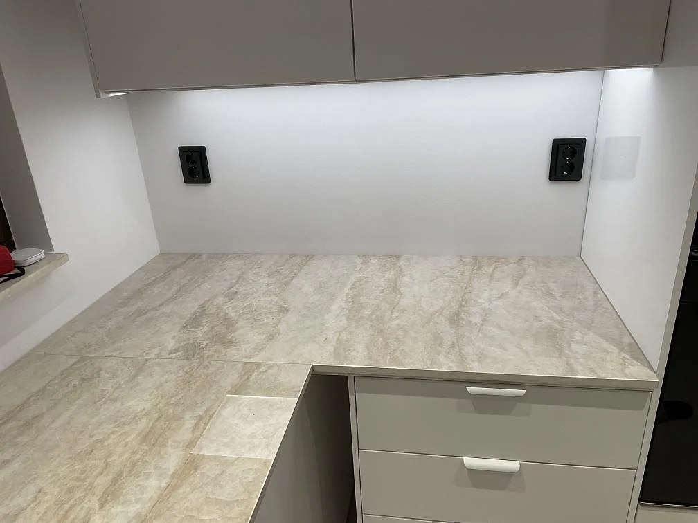 Väggbänk i polerad Dekton Arga under överskåp i ett ljust kök i Bunkeflostrand.