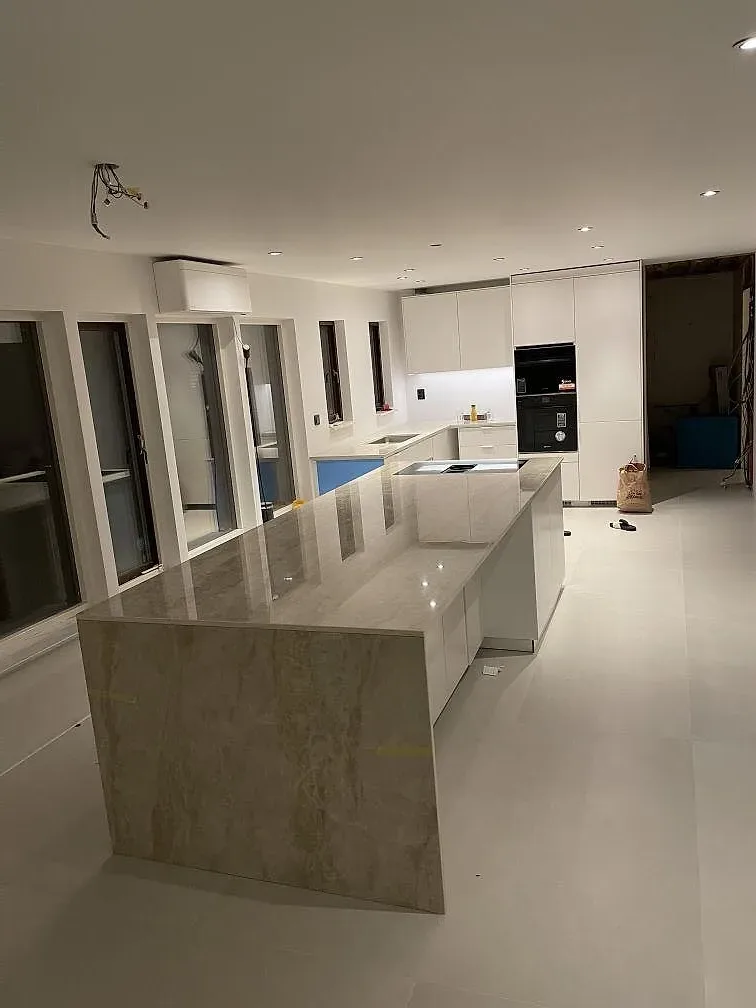 Översiktsbild av kök med köksö och bänkskivor i polerad Dekton Arga i Bunkeflostrand.