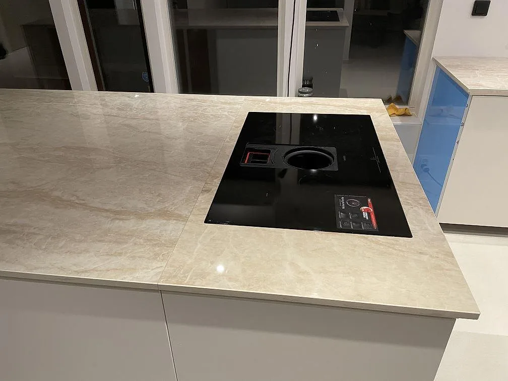 Polerad köksbänkskiva i Dekton Arga med svart häll monterad i köksön i Bunkeflostrand.